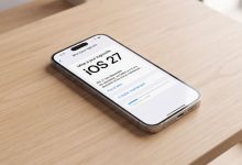 Un iPhone affichant l'écran de mise à jour logicielle iOS 27 sur une table en bois moderne.
