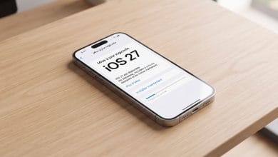 Un iPhone affichant l'écran de mise à jour logicielle iOS 27 sur une table en bois moderne.
